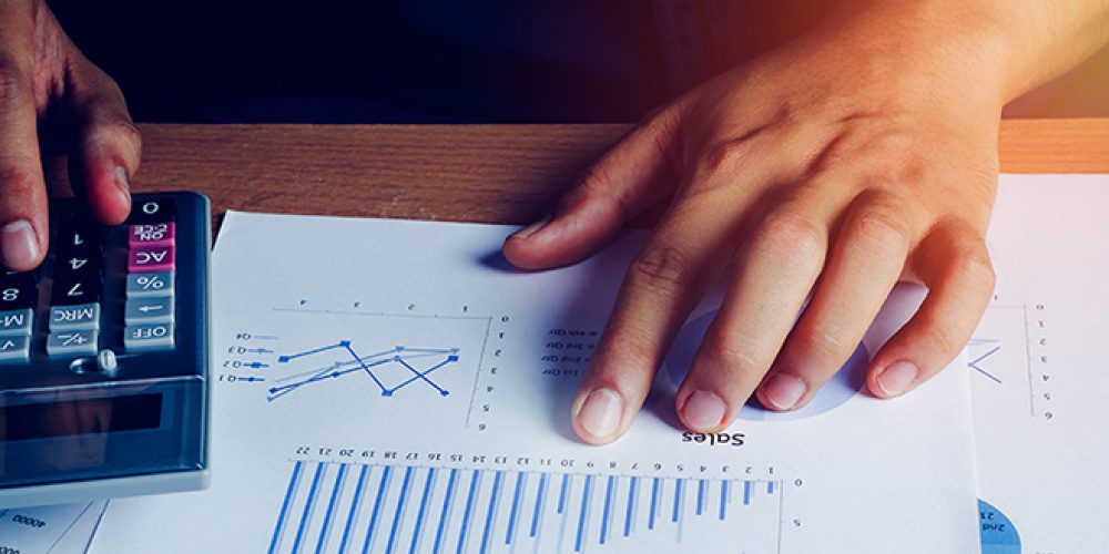 Selective focus hand asian business man is calculating finance and accounting with growth up paper chart on wood table in home office.Pen calculator graph document on desk.economy,saving,financial.